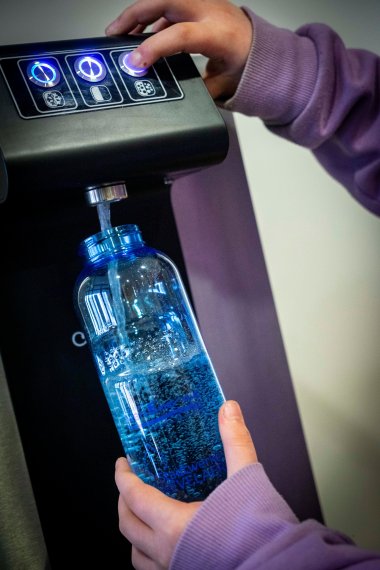 A bottle is filled at a drinking water dispenser