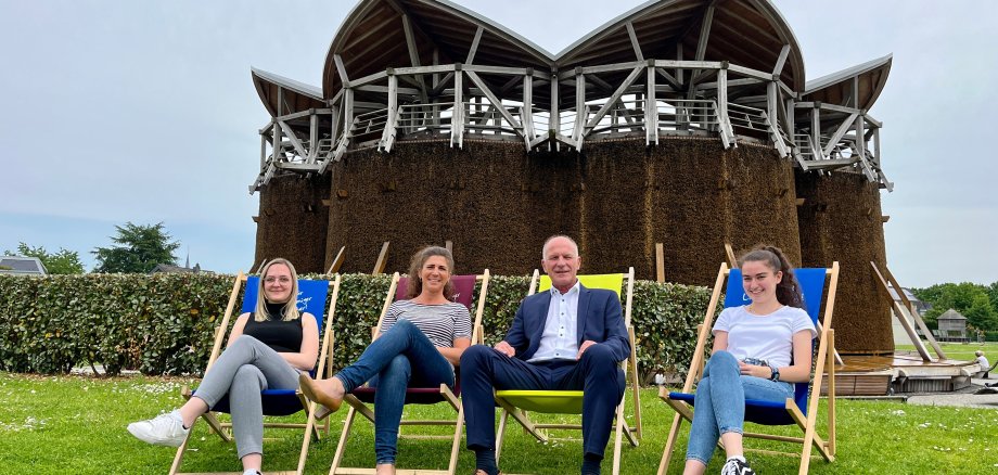 Employees sit on chairs in front of the graduation tower