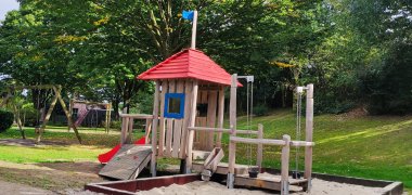 A large wooden climbing frame with a sandpit in a playground.