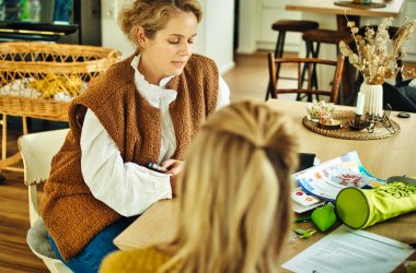 Vrouw toont moeder met baby informatiemateriaal