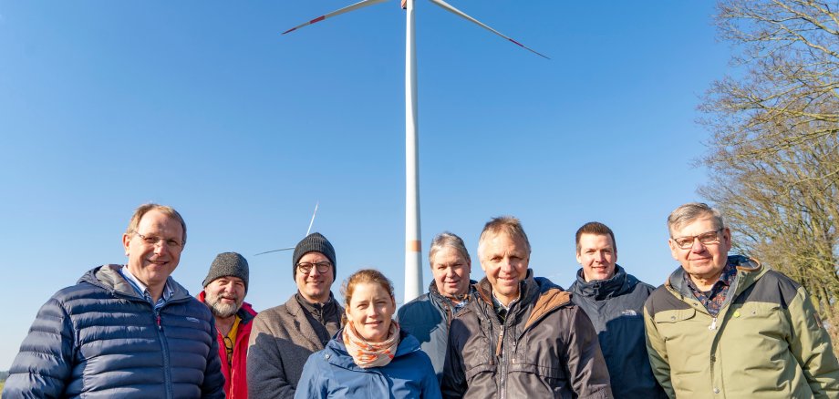 Verschillende mensen staan voor een windturbine