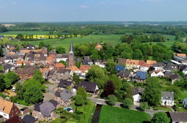 Widok z lotu ptaka na wioskę z kilkoma domami i dużą ilością lasów