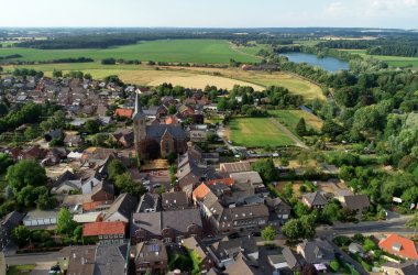 Widok z lotu ptaka na wioskę z kilkoma domami i dużą ilością lasów